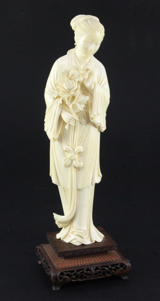 A Chinese ivory figure of a lady holding a flowering peony branch, early 20th century, total height 30cm